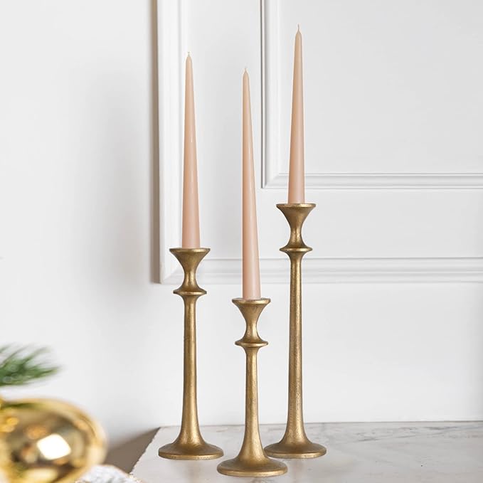 Brass taper candle holders set of three with cream candles, staggered on display.