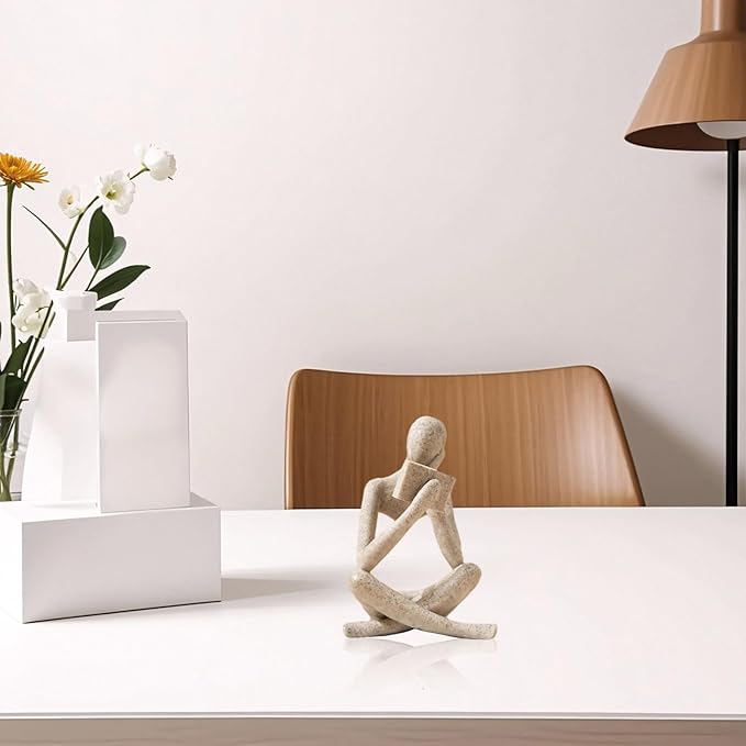 Beige resin reading thinker statue bookend, seated reading pose on white shelf