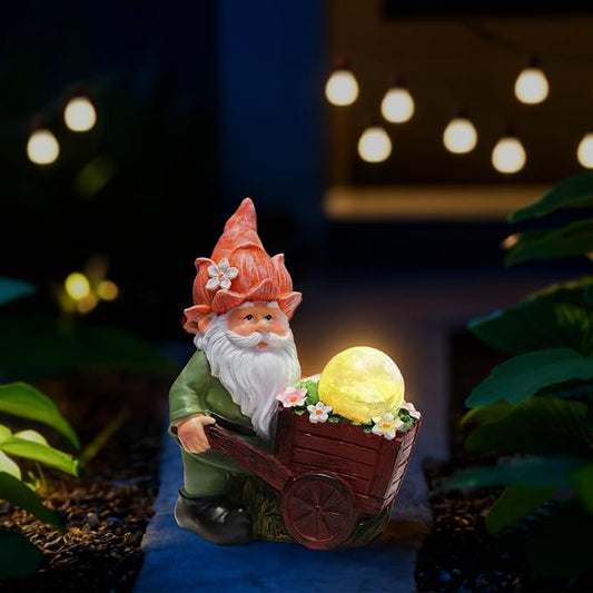 Green garden gnome statue in dark red wheelbarrow with glowing crackle globe light