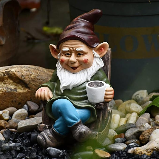 Garden gnome figurine holding a white coffee mug, seated on a wooden chair, green outfit