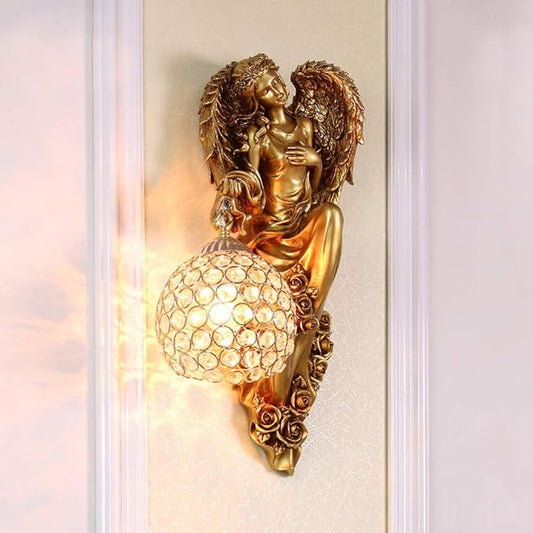 Gold angel wall sconce holding a clear crystal globe shade