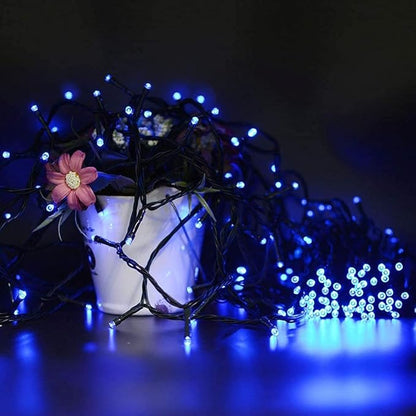 Blue mini LED string lights on dark wire near a pink flower accent