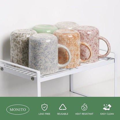 Set of 6 speckled ceramic mugs with curved handles displayed on a white rack