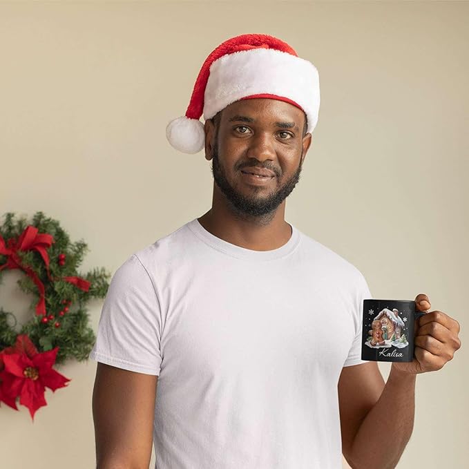 Black ceramic mug with gingerbread house graphic and “Kalisa” name, held in hand.
