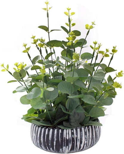 Faux eucalyptus plant with green leaves in dark ribbed rustic cement pot