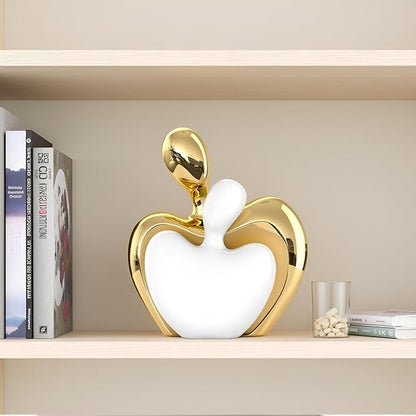 White and gold ceramic couple figurine on mantel shelf, abstract heart with raised arms
