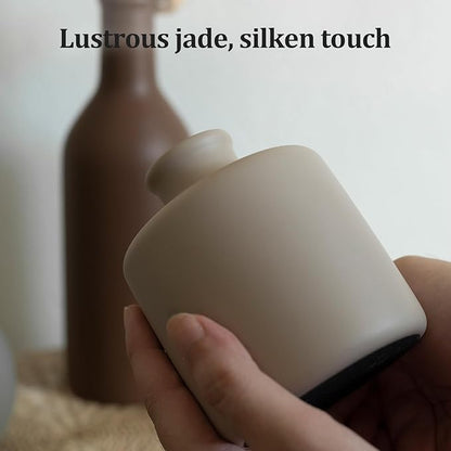 Matte ceramic vase with rounded shoulder in brown, held by hand