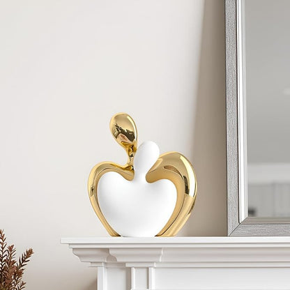 White and gold ceramic hugging couple figurine near a mirror, heart-shaped design