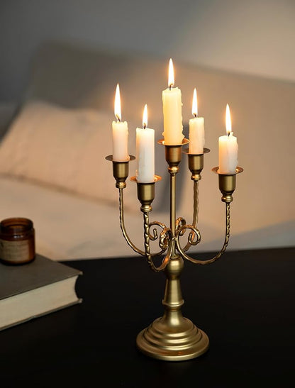 Gold 5-arm metal candelabra with five lit taper candles on a pedestal base