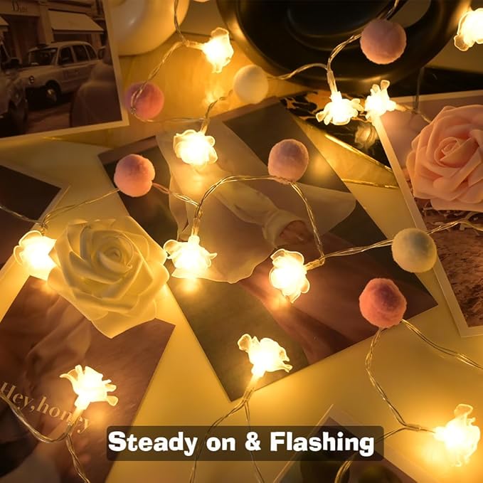 Warm rose LED fairy lights with small pink and orange pom-pom accents on a garland