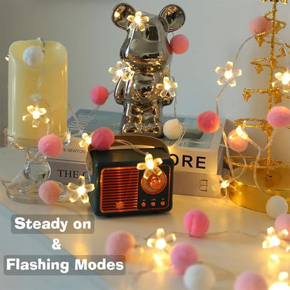 Fairy string lights with pink and white pom-poms and flower-shaped LED bulbs