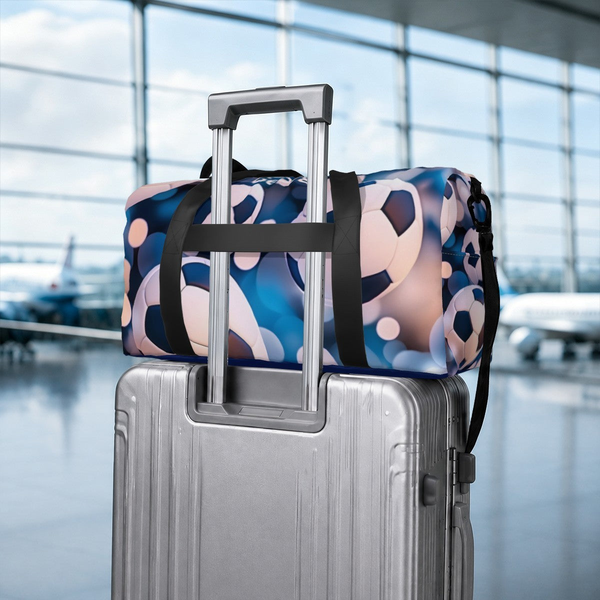 Soccer duffel bag stacked on a rolling suitcase with black strap handles and patterned fabric