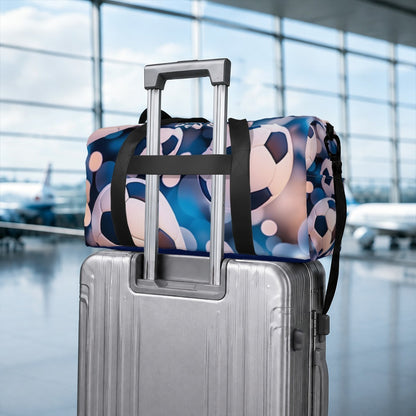 Soccer duffel bag stacked on a rolling suitcase with black strap handles and patterned fabric
