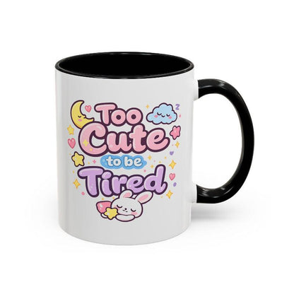 White mug with black rim and handle, kawaii bunny “Too Cute to be Tired” design on front.