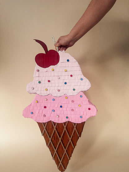 Pink ice cream sundae piñata with colorful sprinkles and red cherry, brown waffle cone