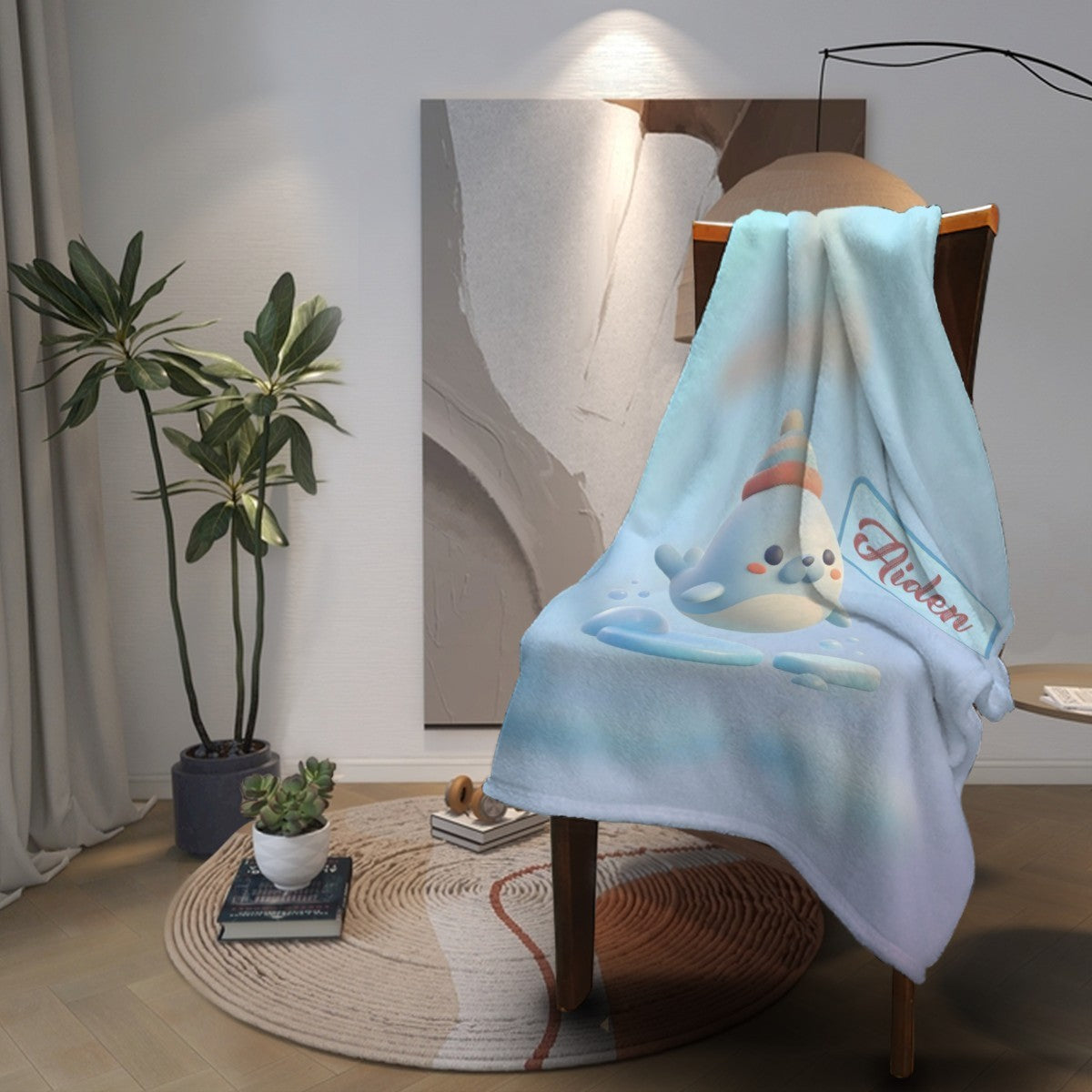 Light blue plush blanket with seal character, “Aiden” logo, and scalloped edge