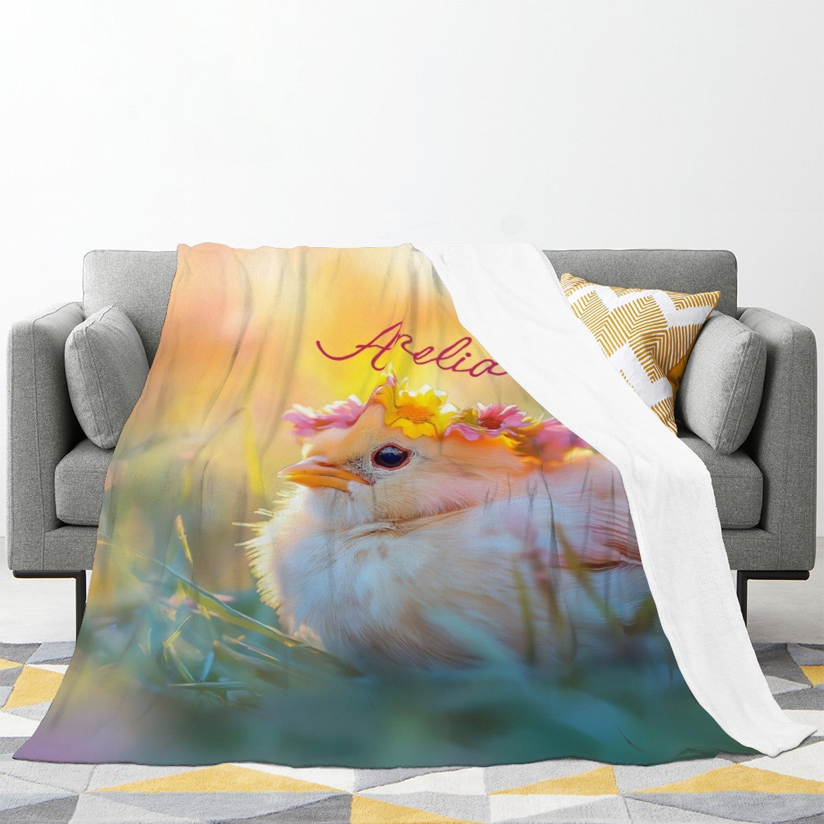 Personalized blanket draped on a sofa, featuring fluffy bird with flower crown and name text