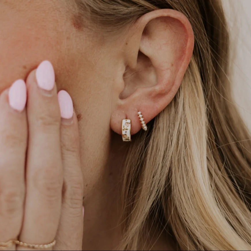 Gold enamel huggie hoop worn beside a slim beaded hoop earring