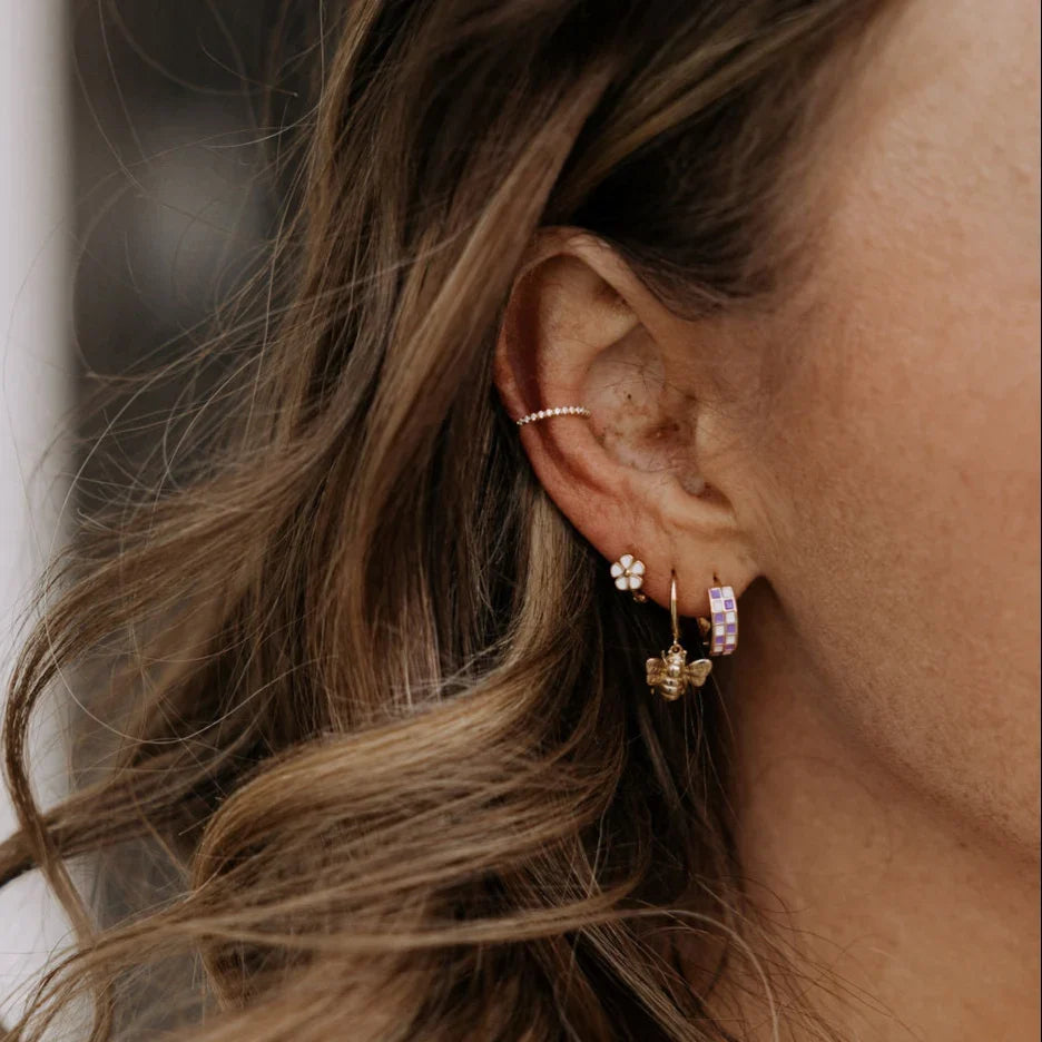 Purple checkered gold-filled huggie hoop worn among other earrings