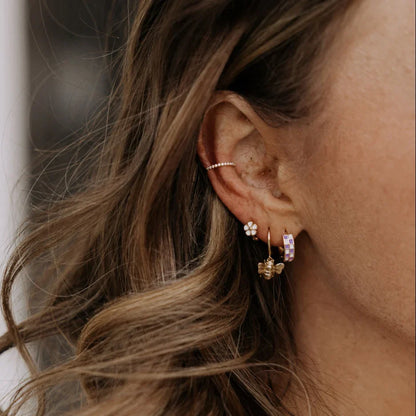 Purple checkered gold-filled huggie hoop worn among other earrings