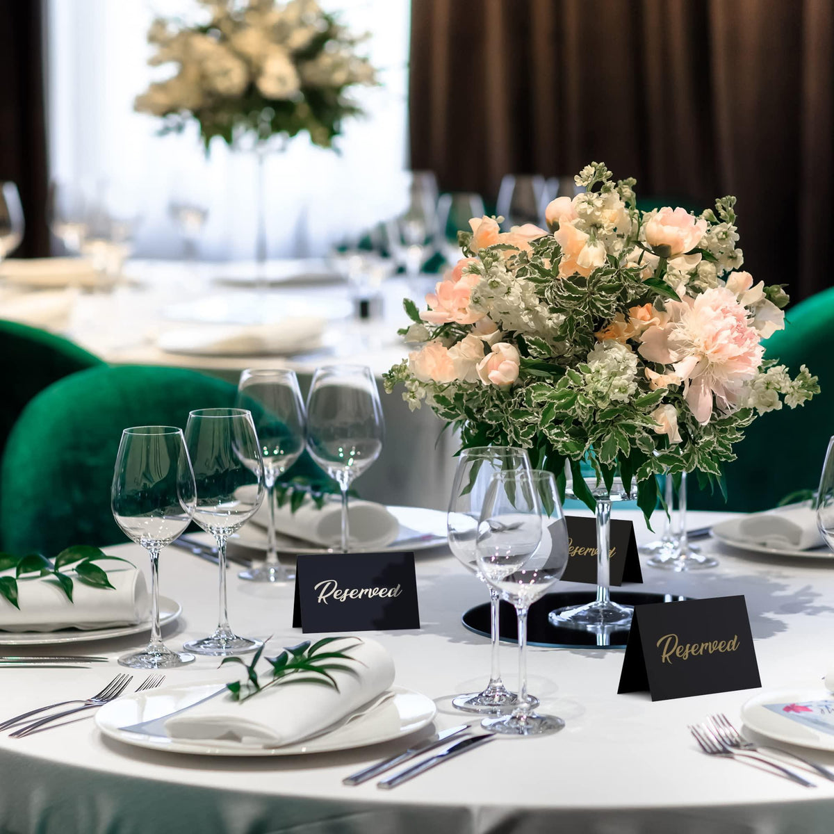 Table setting with black tent cards showing gold-foil “Reserved” name signs