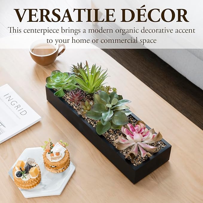 Black faux succulent planter box on a tabletop with green and pink plants