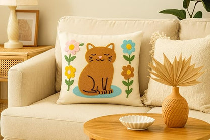 Cream cushion cover with embroidered orange cat sitting on blue grass with flowers