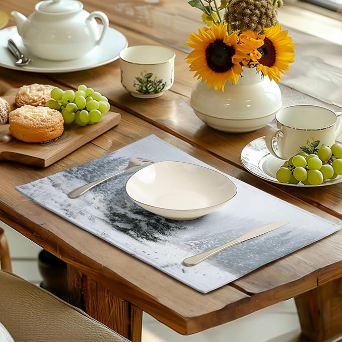 Winter placemat on dining table, snowy pine print under teacups and plates.