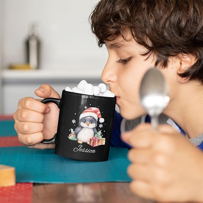 Black mug with penguin Santa hat graphic and name Jessica, held up to drink