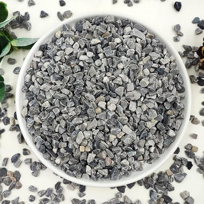 Gray polished stone pebbles in a white bowl, mixed sizes for pots and vases