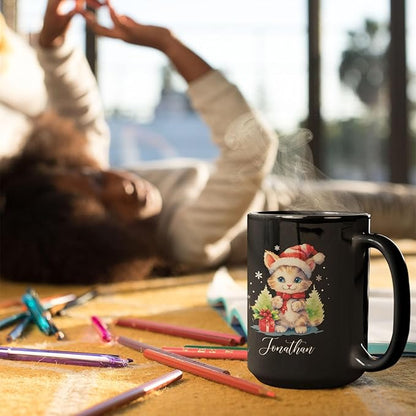 Black mug with kitten holiday artwork and 'Jonathan' near colored pencils on a desk.