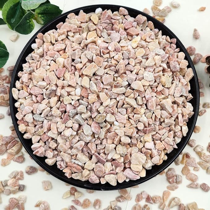 Peach-colored natural stone pebbles in a black tray, light pink and tan stones