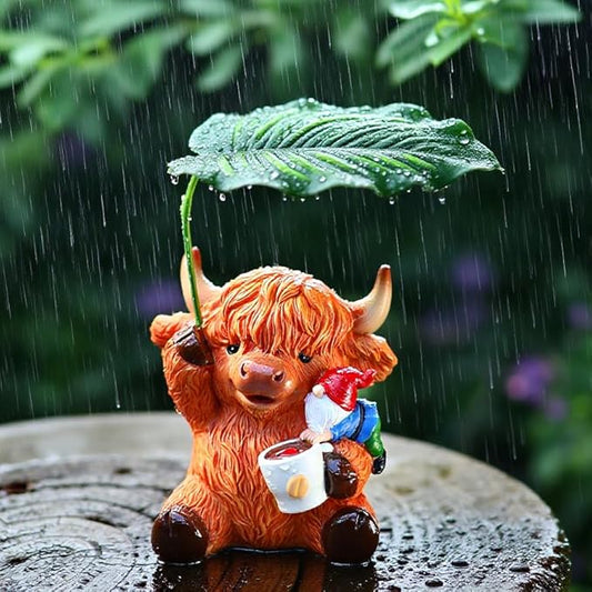 Garden yard ornament: orange Highland cow figurine with red scarf and green leaf parasol.