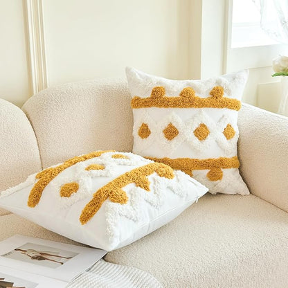 Two white tufted pillow covers with gold boho pattern, one propped and one folded