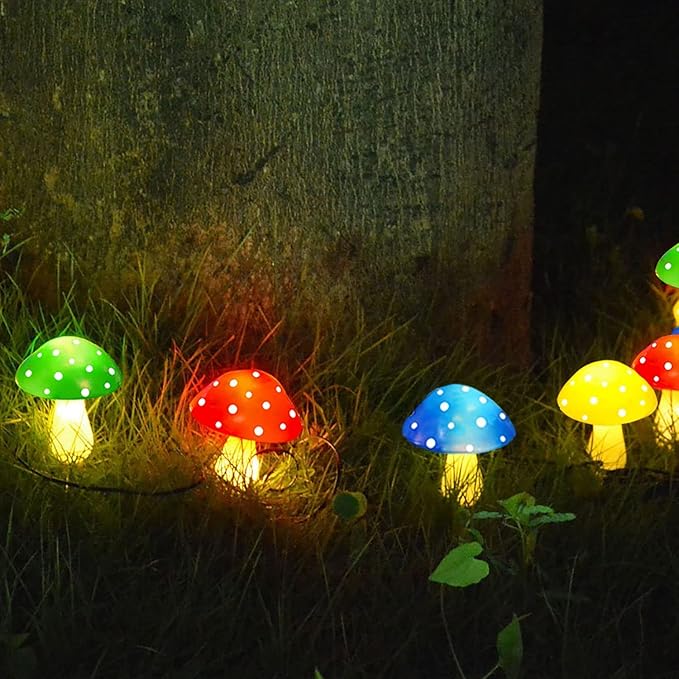 Solar mushroom LED lights with green, red, blue, and yellow dotted caps glowing near grass