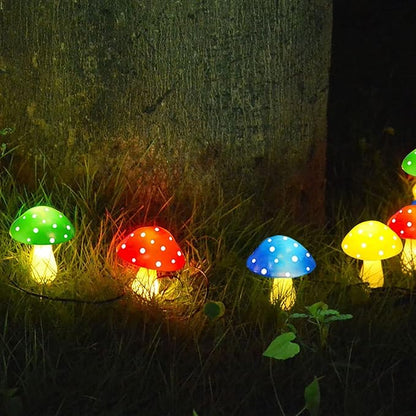 Solar mushroom LED lights with green, red, blue, and yellow dotted caps glowing near grass