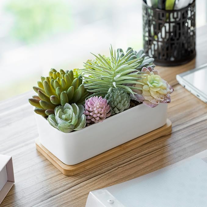 White ceramic faux succulent planter with assorted green and pastel succulents on bamboo base
