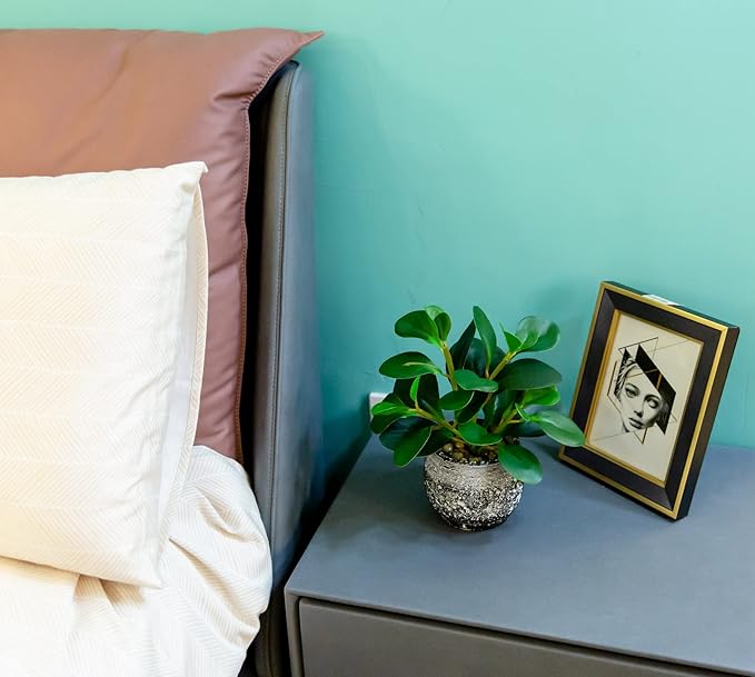 Faux ficus plant in speckled black cement planter on blue side table