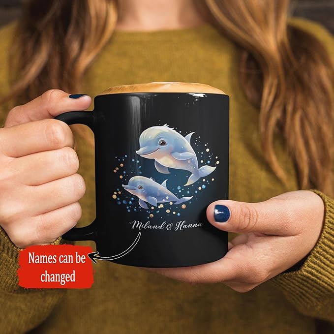 Hands holding black dolphin mug with two blue dolphins and sparkles, custom name