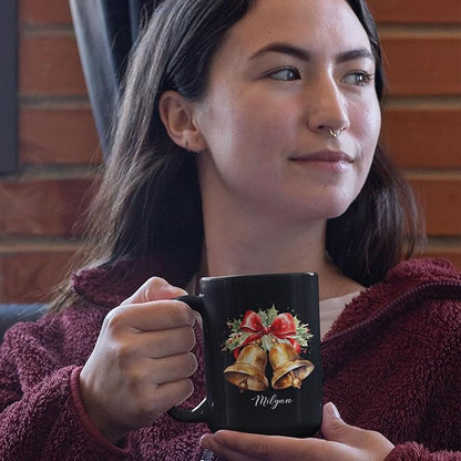 Black ceramic mug with bell and bow print and Milyan script, held near face