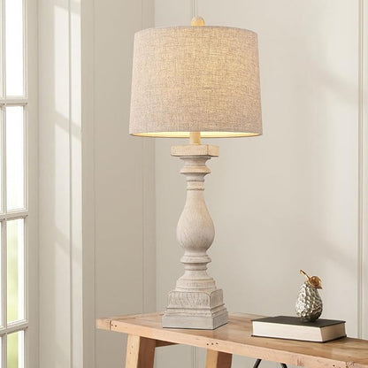 Farmhouse table lamp with beige linen shade and carved resin base on side table