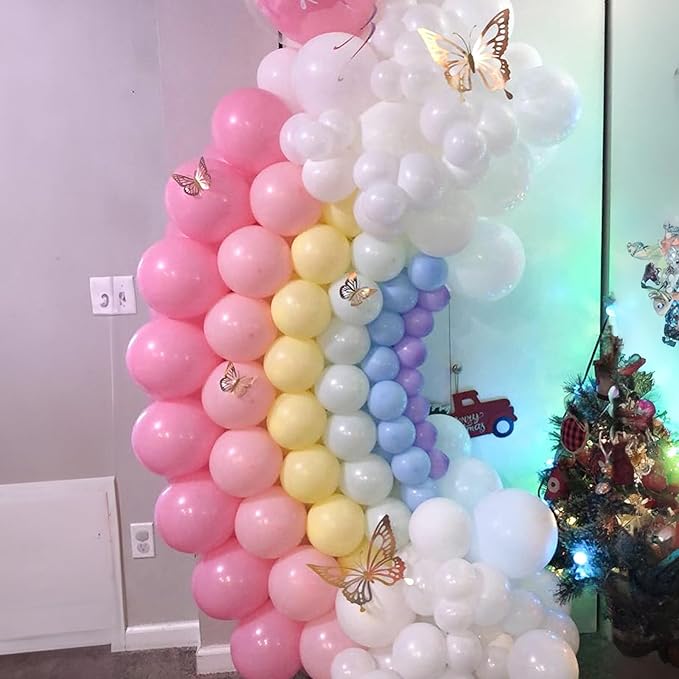 Tall rainbow balloon column with pink, yellow, blue, and white balloons plus gold butterfly accents