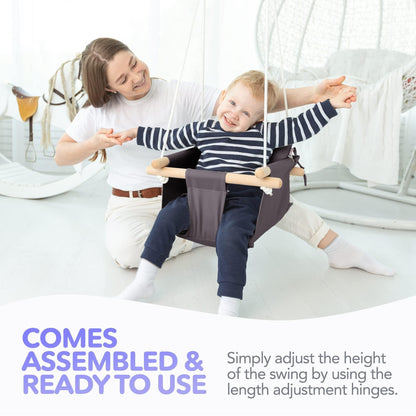 Baby in dark gray hanging swing chair with wooden dowels while parent holds the frame