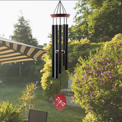 Outdoor wind chime with black tubes and red dragonfly disc, suspended in garden.