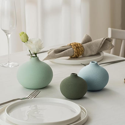 Three mini ceramic bud vases on table in mint, sage green, and light blue