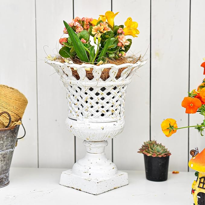 Antique white openwork urn planter with pedestal base, decorated with colorful blossoms