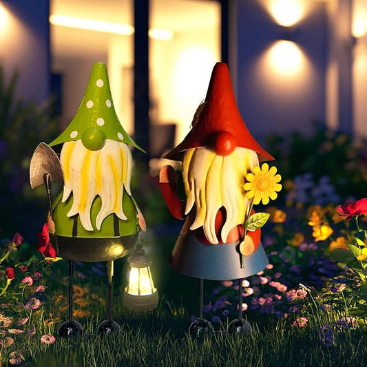 Metal garden gnome statues, red and green hats, holding lanterns with warm light