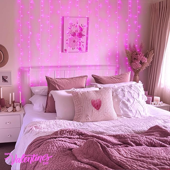 Pink LED curtain string lights glowing behind a bed with pillows