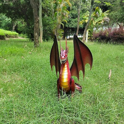 Red and gold dragon figurine on grass, front-facing view with raised wings