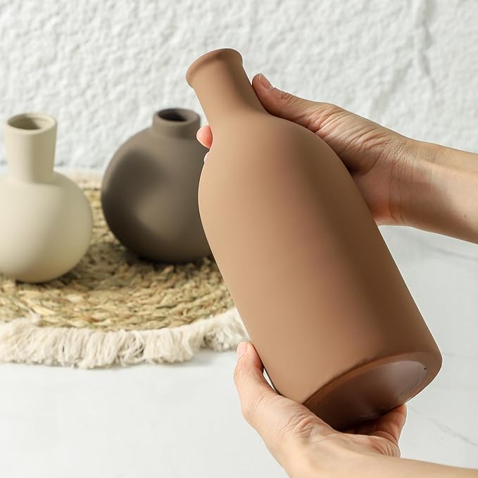 Ceramic vase in terracotta-brown with matte finish, shown being held by hands